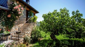 A stone house with a wooden staircase and a garden with a large tree. - Ruralmédulas Las Médulas - El Bierzo house 4 (Carucedo)