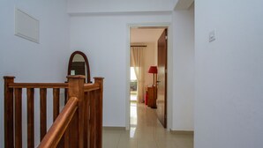 Ein Flur mit einer Holztreppe, einem Spiegel und einer Tür zu einem weiteren Zimmer.