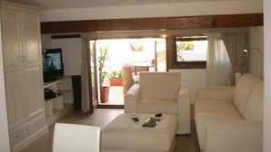 A living room with a television, a sofa, and a window with curtains. - Top floor penthouse apartment with terrace in the historical center, 3 km from the beach (Oristano)