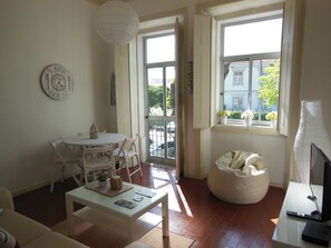 A living room with a round table, chairs, a bean bag, a glass coffee table, and a TV. - White Seagull House in Setubal (Setúbal)