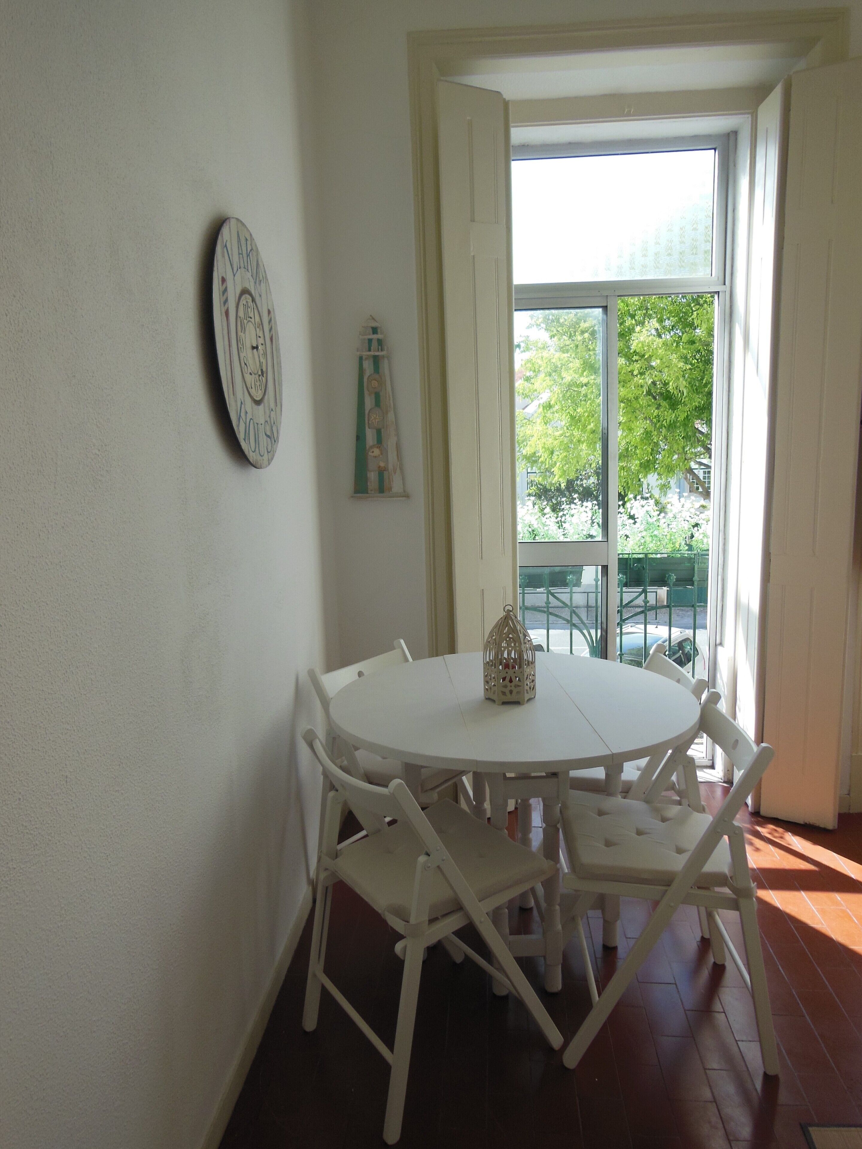 Une table à manger blanche avec quatre chaises, une horloge murale et un objet décoratif.