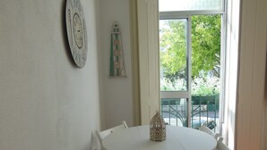 Uma mesa de jantar branca com quatro cadeiras, um relógio de parede e um objeto decorativo.