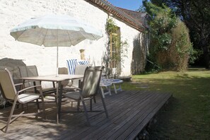 Relax on the patio with a wooden deck, table, and comfortable chairs under a large umbrella.