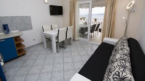 A modern hotel room with a dining area, a sofa, and a view of the sea.