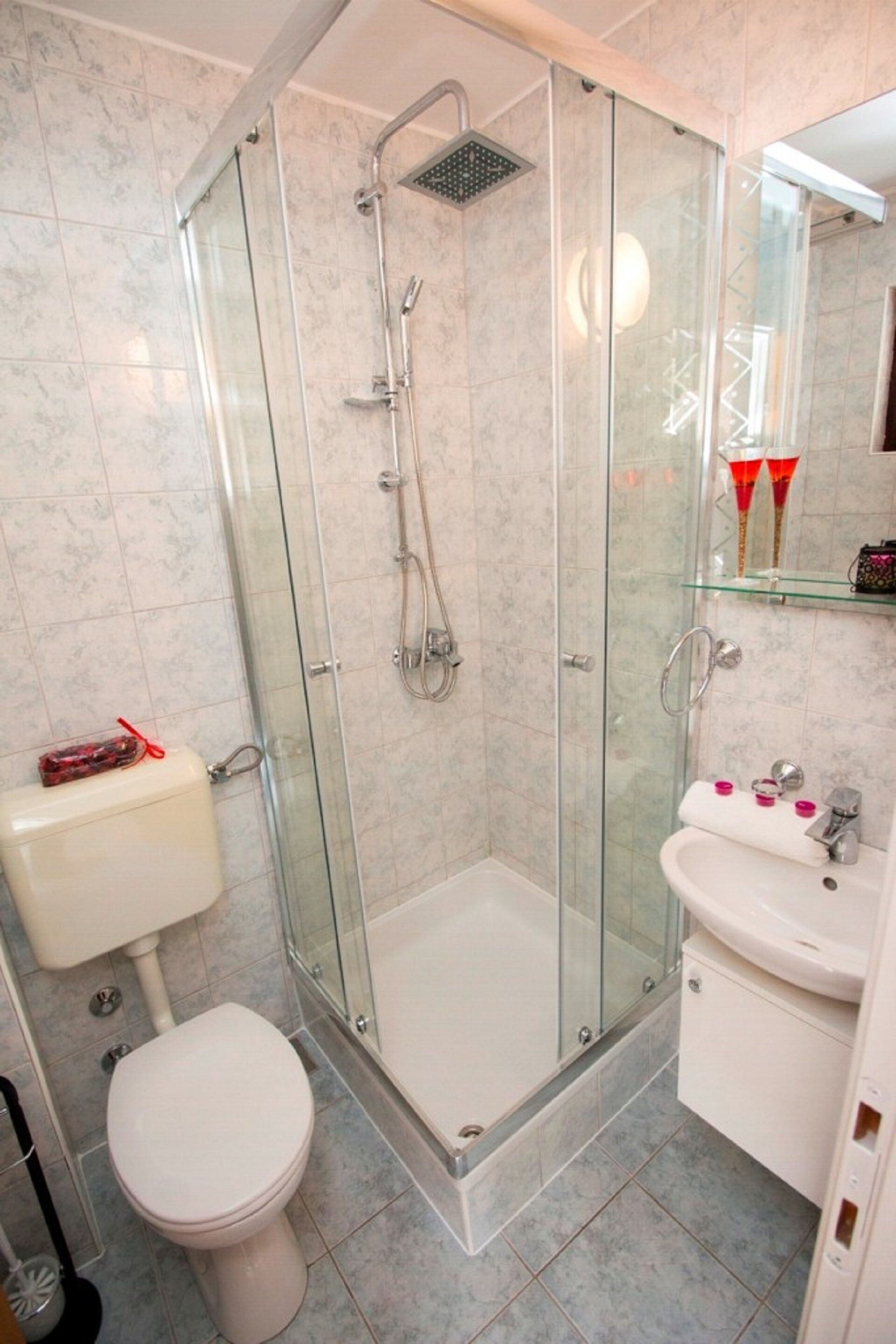 A modern bathroom with a glass-enclosed shower, a toilet, and a sink.
