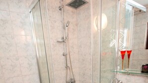 A modern bathroom with a glass-enclosed shower, a toilet, and a sink.