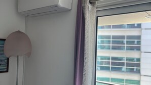 A room with a window, a curtain, a wall-mounted air conditioner, and a floor lamp. - Nobel Apartment in Park of Nations.  EXPO, ORIENTE & AQUARIUM VASCO DA GAMA (lisboa)