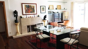 A living room with a glass dining table, two chairs, a fireplace, and a television. - Nobel Apartment in Park of Nations.  EXPO, ORIENTE & AQUARIUM VASCO DA GAMA (lisboa)