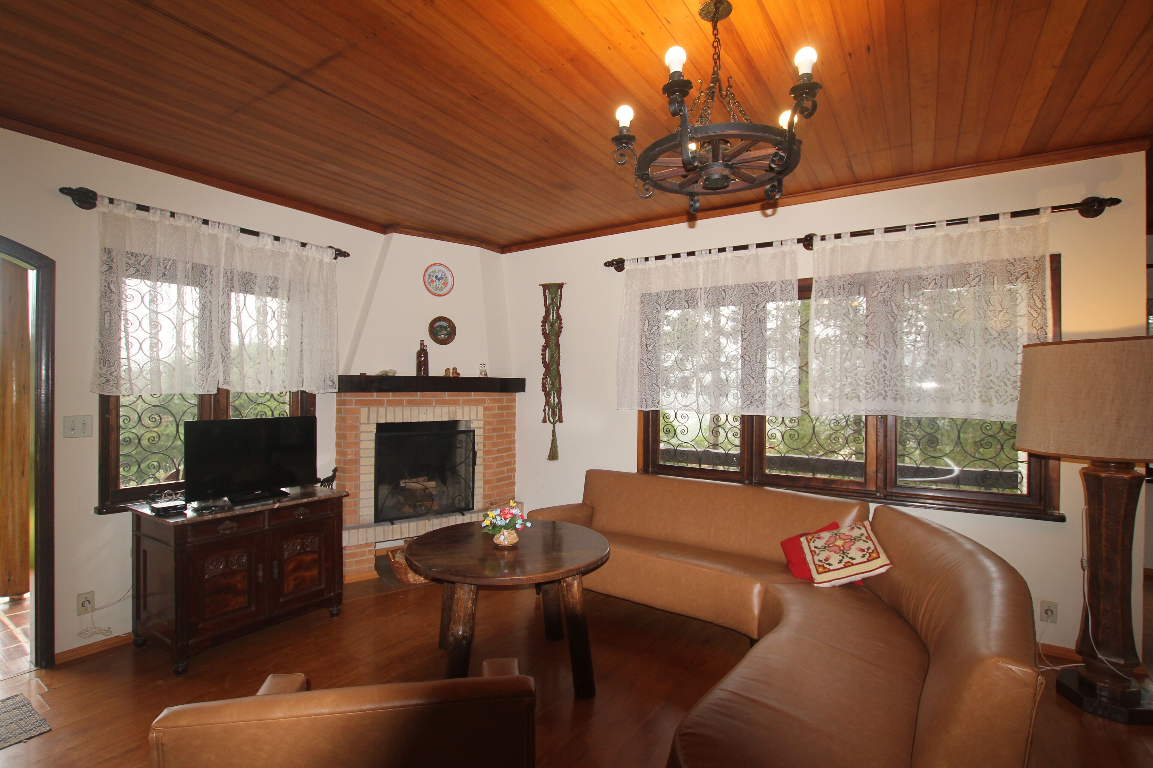 Uma sala de estar com lareira, sofá, televisão e um candelabro.