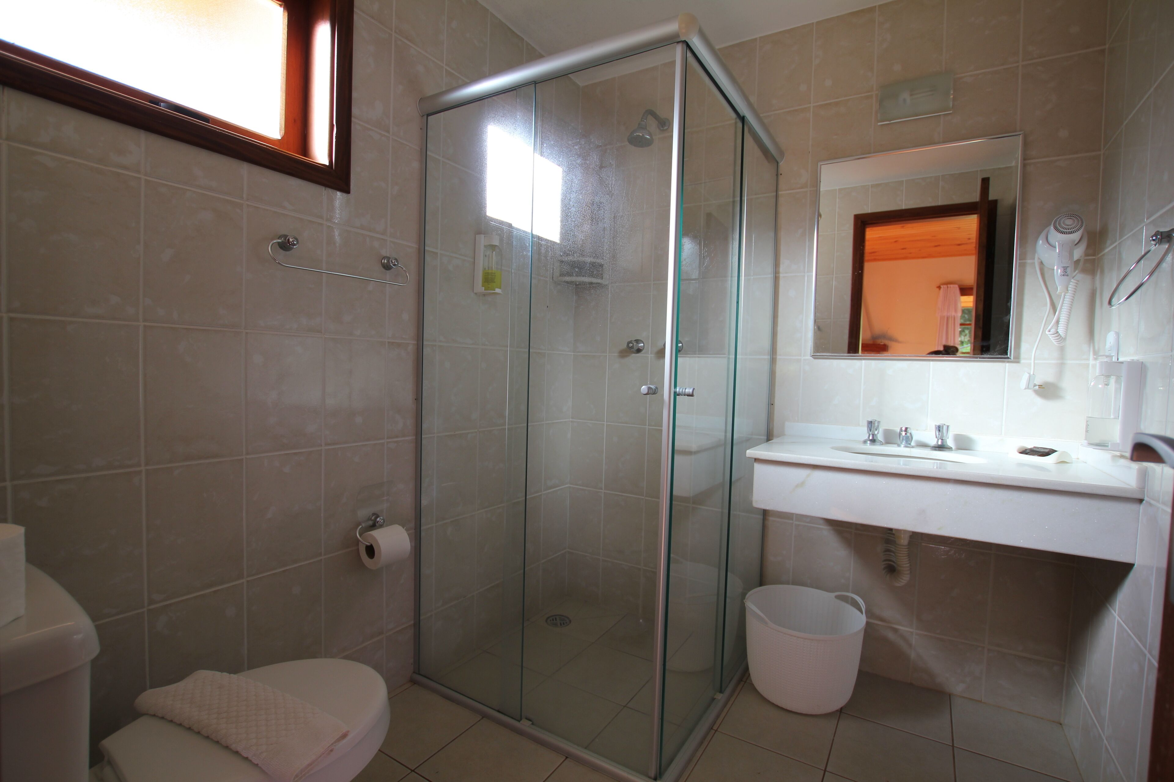 Un baño con ducha de vidrio, inodoro, lavabo y espejo.