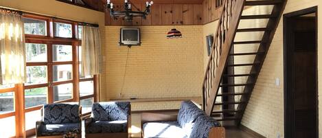 A cozy room with wooden furniture, a TV, and a staircase.
