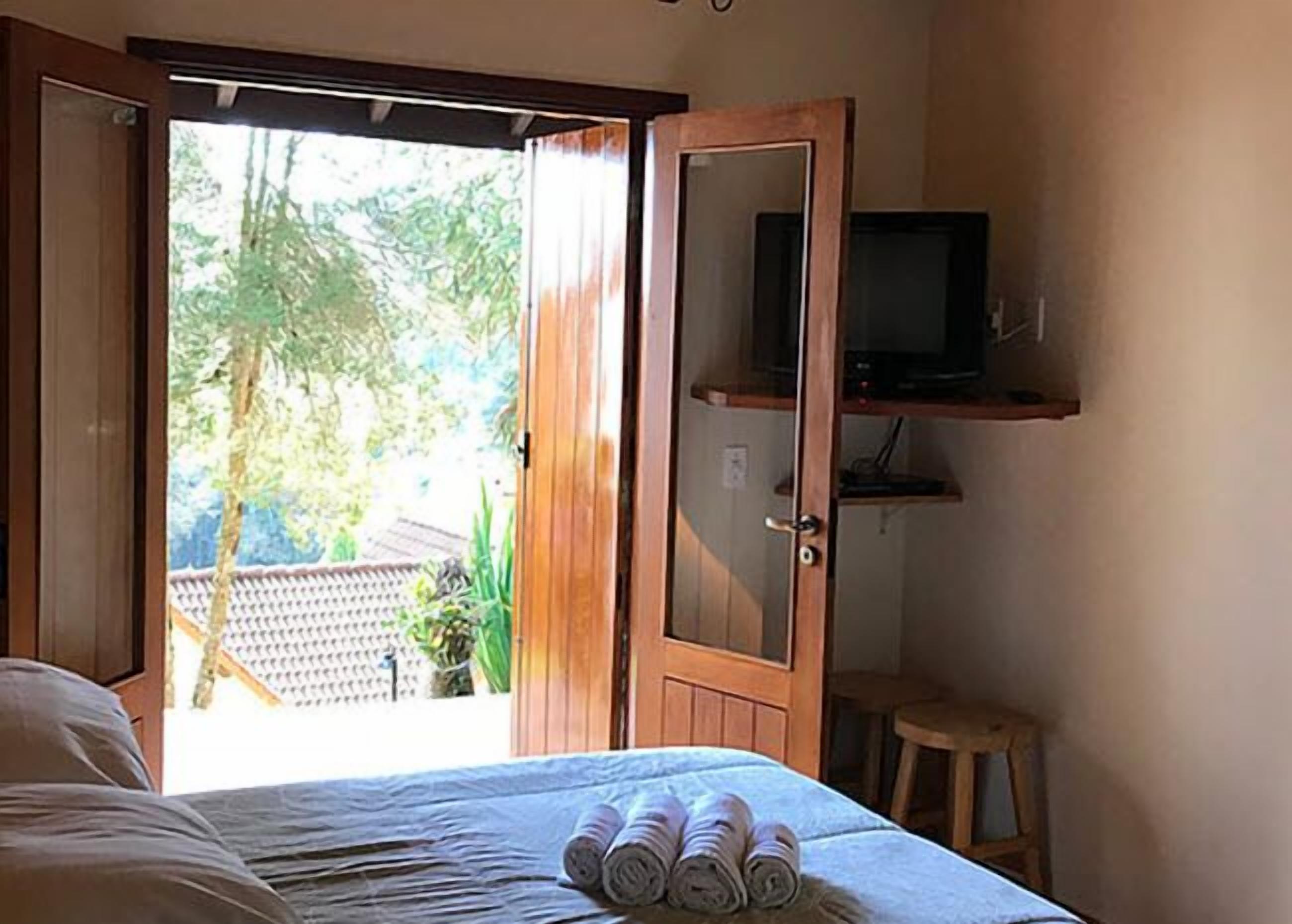 Una habitación con una cama, un televisor en un estante y vistas al exterior.