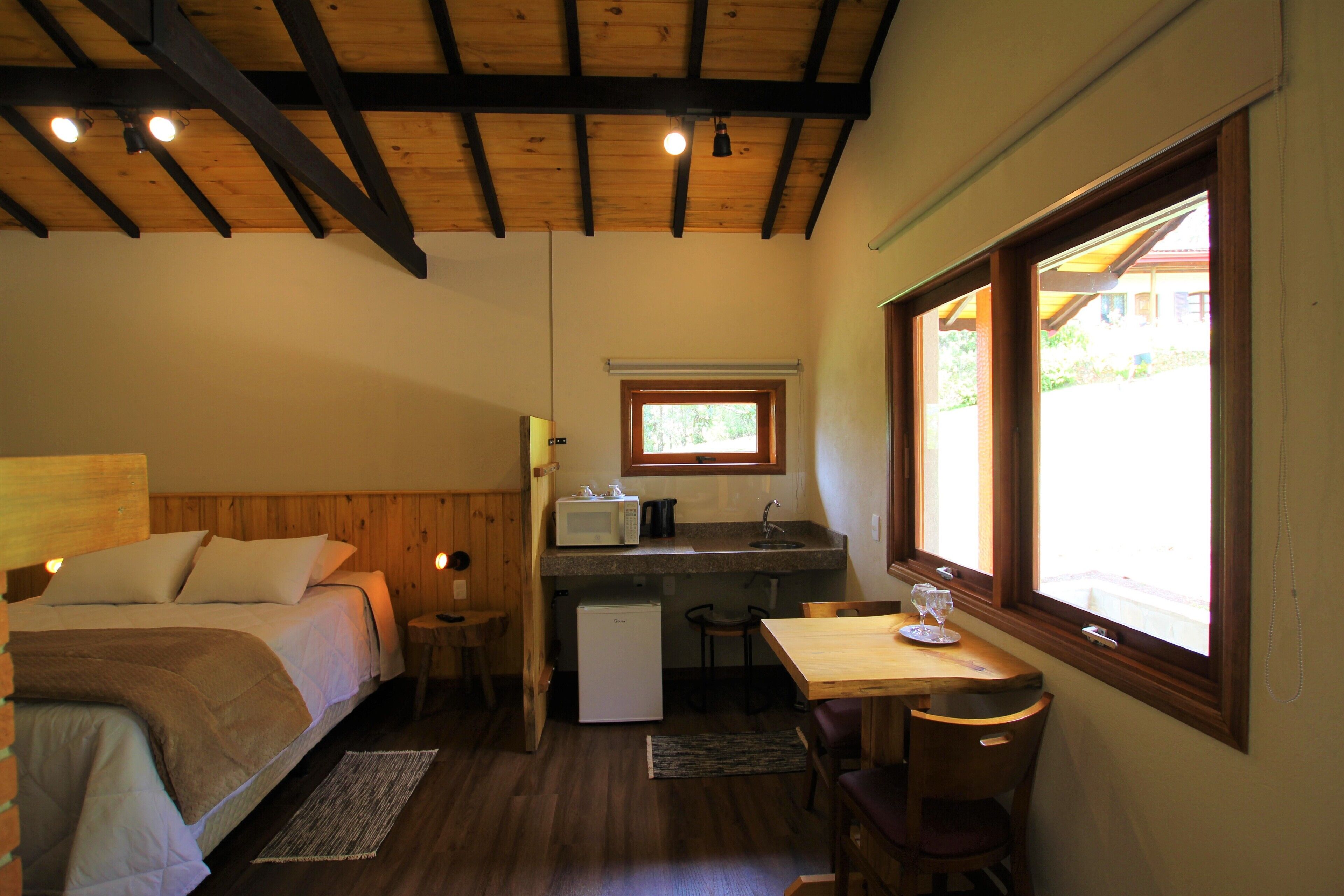 Un dormitorio con cama, un kitchenette pequeño, zona de comedor y ventana con vista.