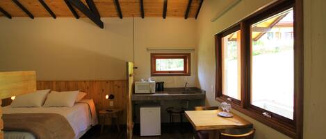 Un dormitorio con cama, un kitchenette pequeño, zona de comedor y ventana con vista.