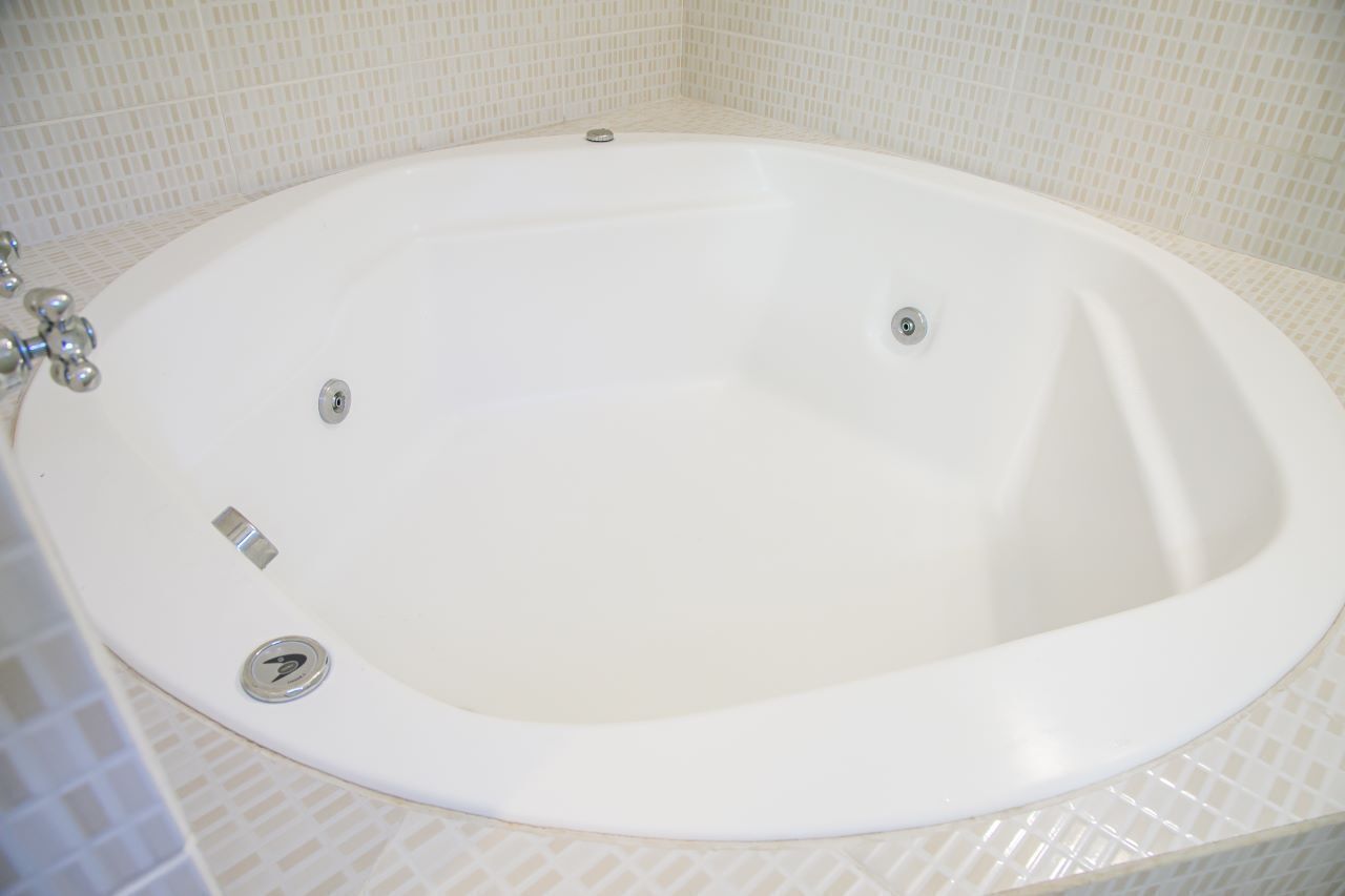 Eine weiße, ovale Badewanne mit zwei Wasserhähnen und einem Abfluss.