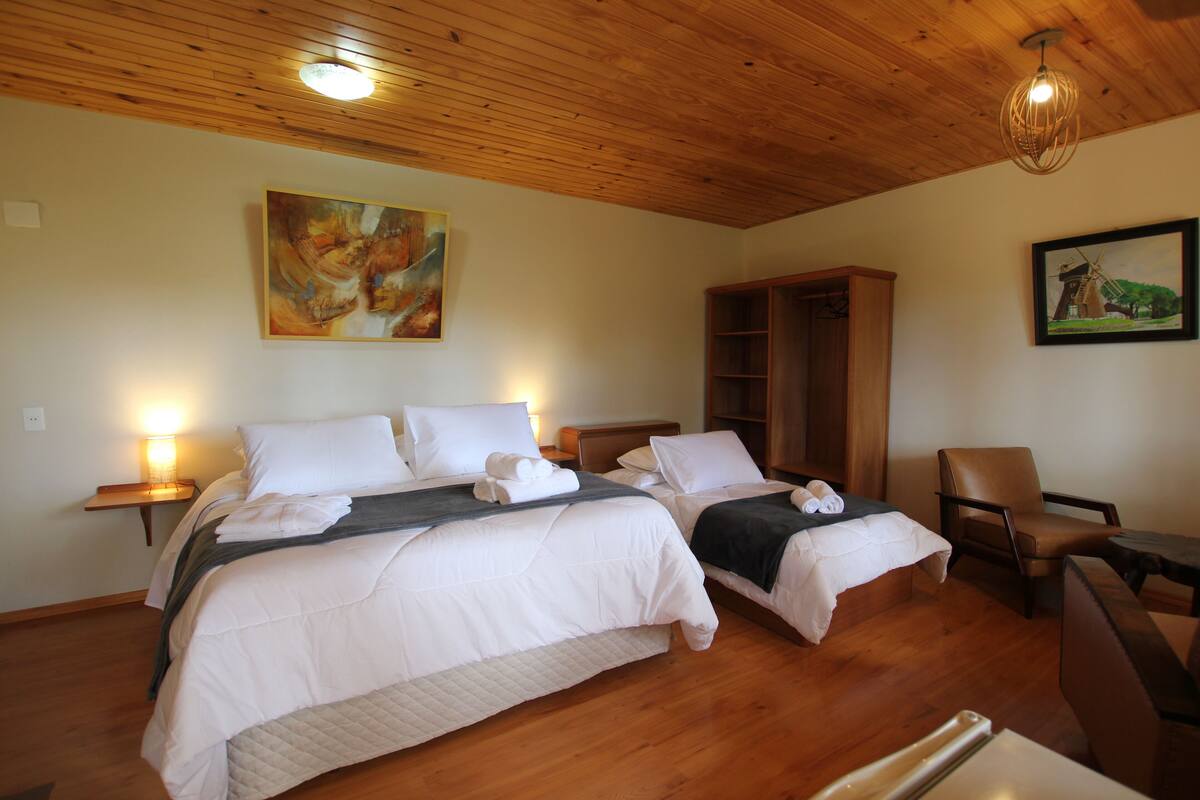 Ein Hotelzimmer mit zwei Betten, Holzboden, einem großen Kleiderschrank und Bildern an den Wänden.