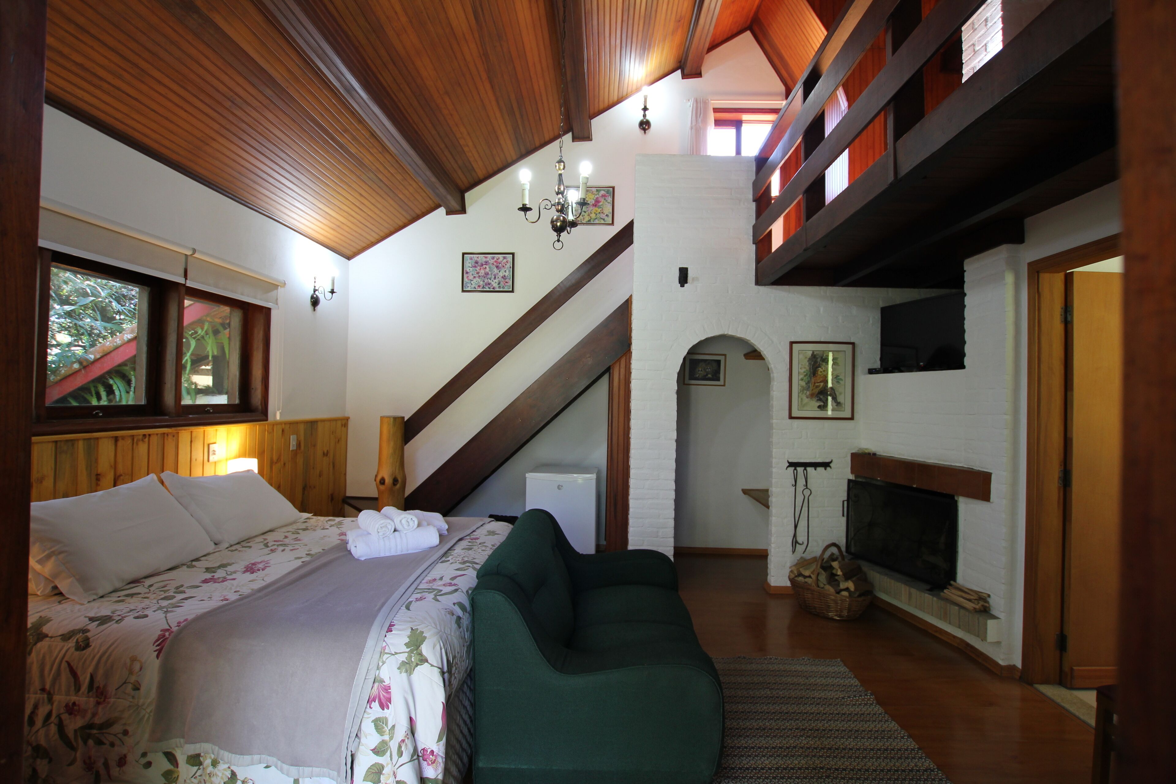 Un dormitorio con una cama, un sofá verde, una chimenea y una escalera.