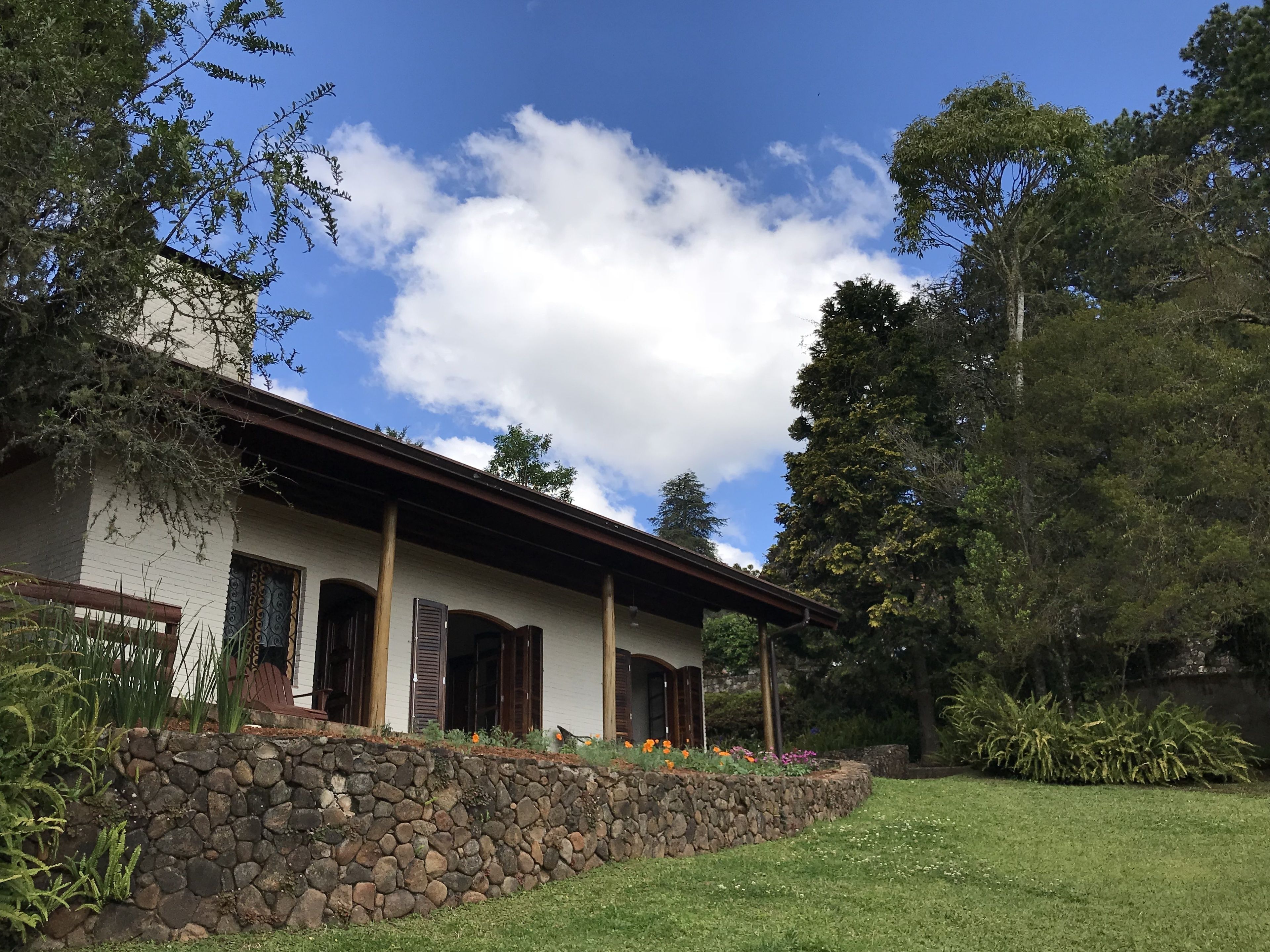 A two-story house with a stone foundation, wooden columns, and a covered porch.