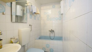 Casa de banho com sanita, lavatório e banheira.