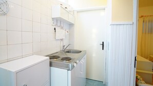Cozinha compacta com pia, fogão e armários brancos.
