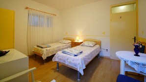 Quarto com duas camas de solteiro, uma escrivaninha e uma cadeira.