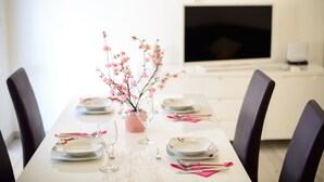 Ett matbord dukat med tallrikar, glas och rosa servetter, och en vas med rosa blommor i mitten.