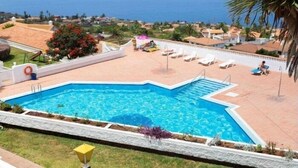 A swimming pool with a clear blue water, surrounded by a white wall and a stone border. - Cozy home in Tenerife with views & pool (Santa Cruz de Tenerife)