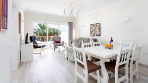 A bright dining area with a white table and chairs, a chandelier, and artwork on the walls. - Cozy home in Tenerife with views & pool (Santa Cruz de Tenerife)