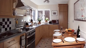 Una cocina con armarios de madera, estufa, microondas y una mesa de comedor lista para una comida.
