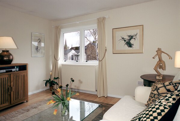 A living room with a sofa, a coffee table, a lamp, a cabinet, and a window with curtains.