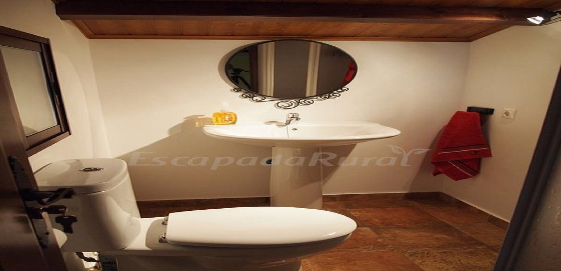 A bathroom with a toilet, sink, and mirror.