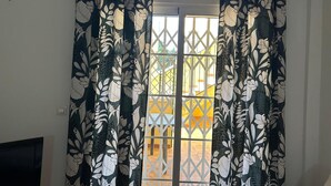A room with a window featuring floral curtains and a view of a yellow building outside. - Ground Floor Apartment in Palomares with Communal Pool (Palomares Almeria)