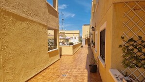 A narrow alleyway with tiled flooring, yellow walls, and a small reception area with a counter and chairs. - Ground Floor Apartment in Palomares with Communal Pool (Palomares Almeria)
