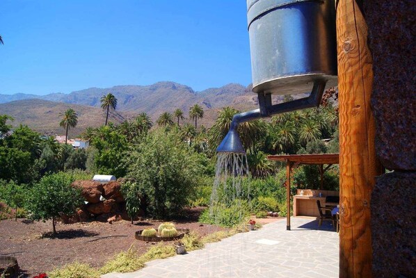 Un jardin agrémenté d’un élément aquatique, de palmiers et dominé par un paysage montagneux.