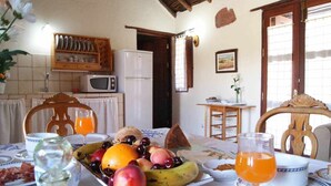 A breakfast setting with a fruit platter, a glass of orange juice, and a table with plates and cups. - Rural House La Fuente de la Flora (Valle, El (Santa Lucia De Tirajana))