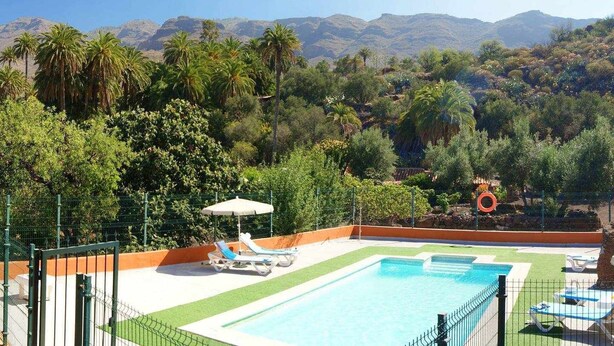 A pool area with lounge chairs and a view of mountains. - Rural House La Fuente de la Flora (Valle, El (Santa Lucia De Tirajana))