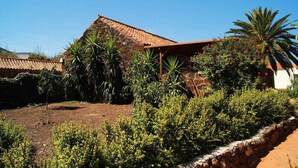 A house with a tiled roof, surrounded by lush greenery and a well-maintained garden. - Rural House La Fuente de la Flora (Valle, El (Santa Lucia De Tirajana))
