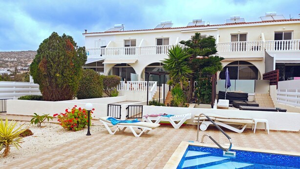 A rooftop pool area with lounge chairs, a swimming pool, and a building with multiple balconies.