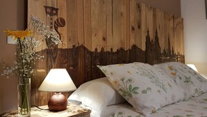 Une chambre à coucher avec une tête de lit en bois, une table de chevet avec une lampe, un vase de fleurs et un lit avec une literie à motifs floraux.