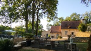 A courtyard with stone walls, a wooden bench, and a building with a tiled roof. - House / Villa - PONTCIRQ (Pontcirq)