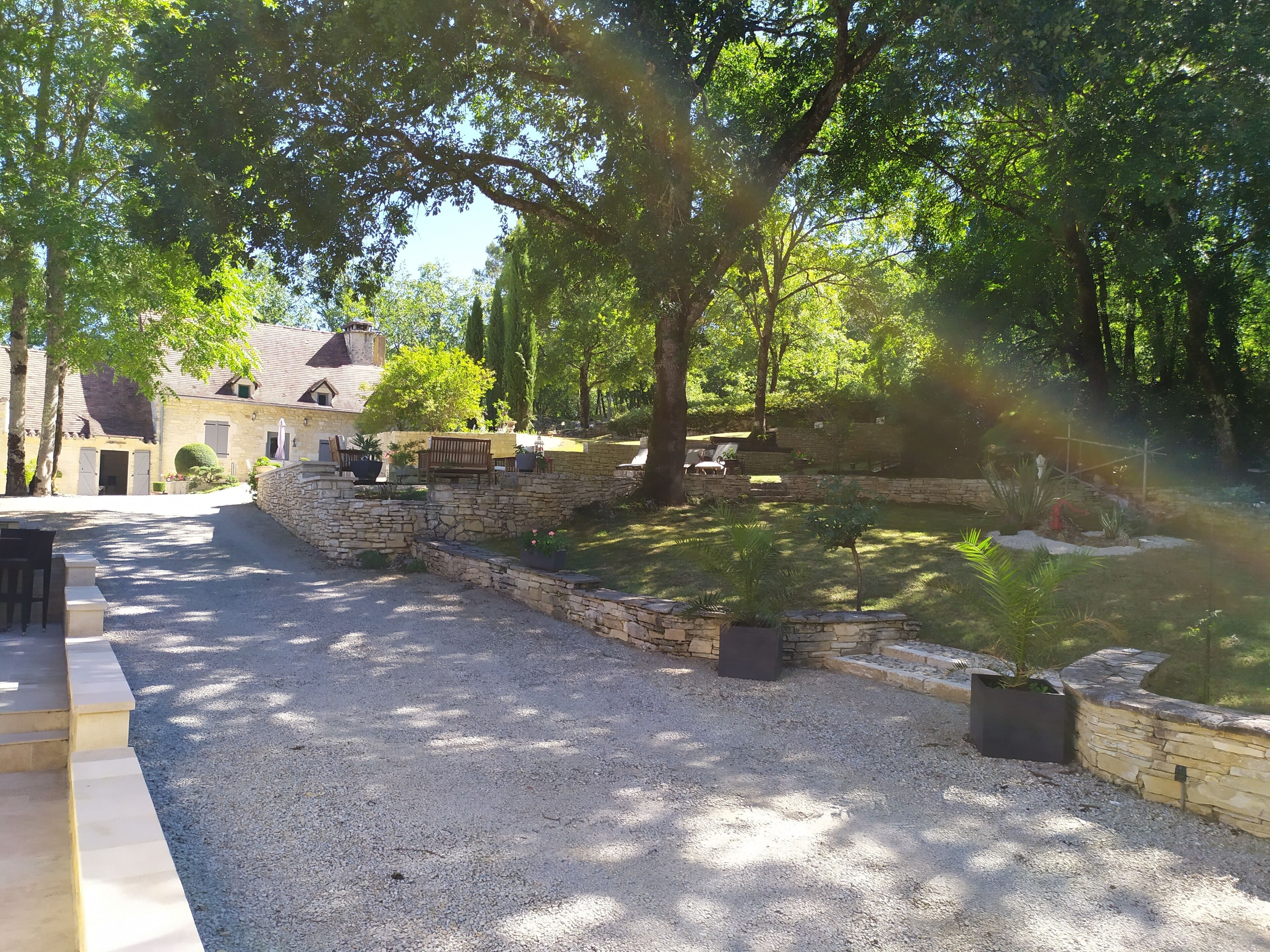 A stone pathway leading to a stone wall with a bench and a small garden area.