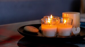 Three lit candles on a tray with a heart-shaped decoration and a stone.