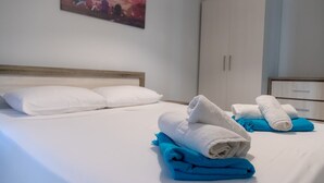 A hotel room with a bed, white pillows, and folded towels in white and blue.