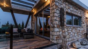 Moderni kivirakennus, jossa on patioalue, jossa on sohva ja nuotiopaikka.