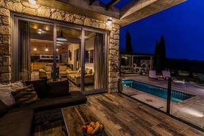 A cozy outdoor seating area with a pool, stone walls, and a view of the interior. - Secluded Villa with Private Pool and stunning views of the Coral Bay coastline (Kathikas)