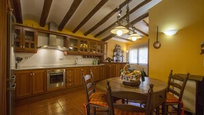 A kitchen with wooden cabinets, a stove, and a dining table with chairs.