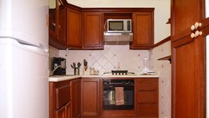 Una cucina compatta con mobili in legno, un forno a microonde, un fornello e un lavandino.