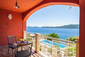 A balcony with a view of the sea, a table with breakfast items, and a chair.