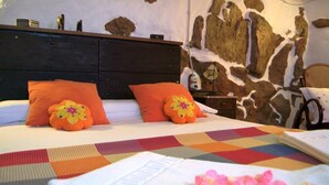 Een bed met oranje kussens, een sprei en een muur met een steenachtige textuur.