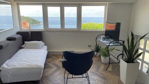 A bedroom with a bed, a sofa, a desk with a chair, and a view of the sea. - Apartment Marijana The most amazing breathtaking view to the sea and Old Town! (Dubrovnik)